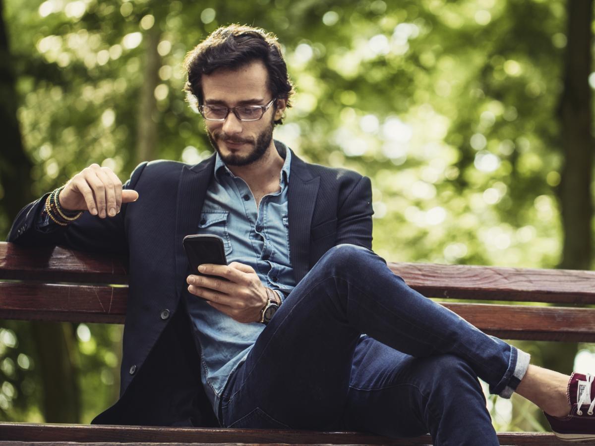 Chill guy using his phone sitting on a bench