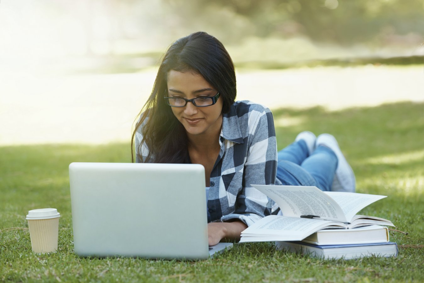 woman working on computer laying on grass in a park